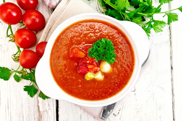 Soup tomato in white bowl with vegetables and parsley on board top