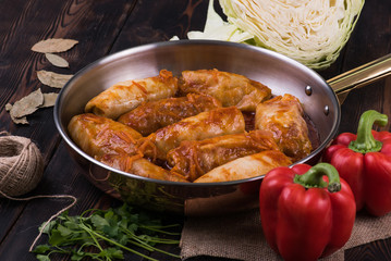 Meat dish in a frying pan on a wooden background with vegetables