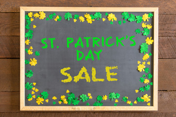 St Patrick's Day blackboard with gold and green shamrock confetti and sale message