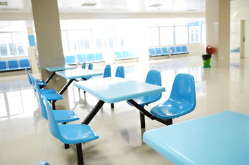 Clean school cafeteria with many empty seats and tables.