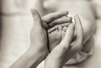 Mother holding tiny foot of newborn baby