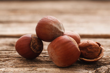 Filbert nuts on wood close-up. Several hazelnuts with one peeled. Brown autumn background. Harvest, fall, food ingredient concept
