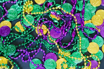 Mardi Gras background with beads and token coins on black © Kelly