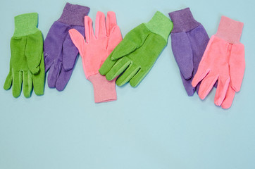 Purple, green and pink gardening gloves on a blue background with lots of copy space