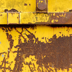 Old rusting metal skip container with yellow pealing paint