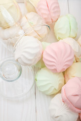 Multicolored marshmallow scattered on a white wooden table