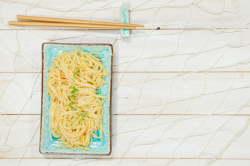 Noodles and on a white board surface with chopsticks and fishnet