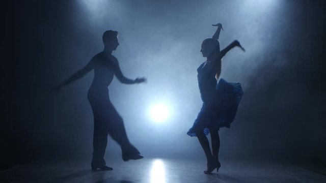 Professional couple of salsa dancers posing in smoky studio, silhouette
