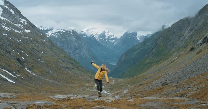 Woman dancing silly freestyle dance outdoors on mountain Crazy dancer girl having fun Independent traveller enjoying nature celebrating vacation travel adventure Norway