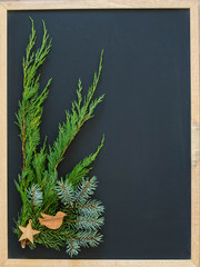 A black chalk board with Christmas greenery and wooden ornaments and room for your text