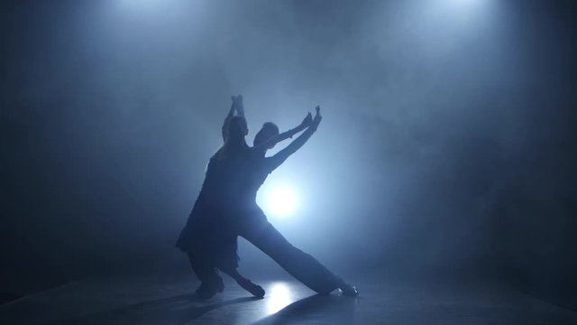 Dance rumba performed by professional couple in smoky studio, silhouette