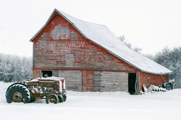 Poster Vintage tractors in front of an old red barn in snow © Kelly