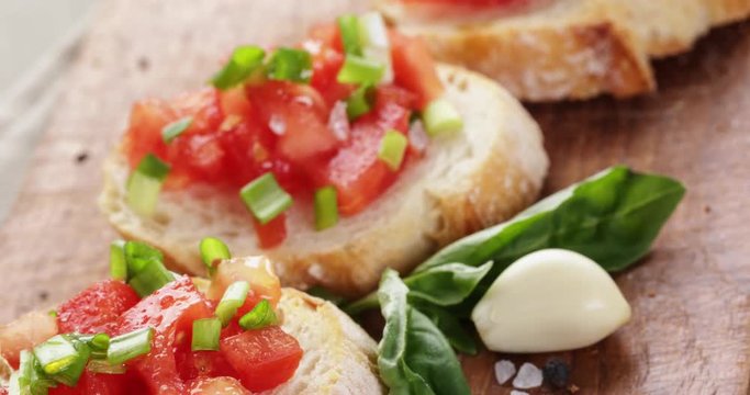 closeup pan of classic italian bruschetta with tomatoes and herbs on wood board, 4k prores footage
