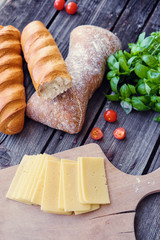 White bread, tomatoes and green basil and cheese on a wooden table.
