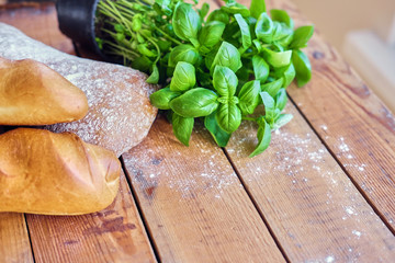 Two pieces of french bread and a green basil on a wooden table.