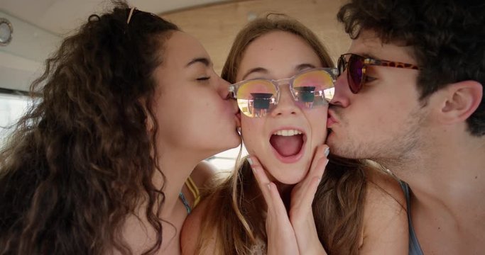 Portrait Beautiful teenage hipster friends posing for camera girl kissing on cheek smiling at festival in camper van on road trip adventure