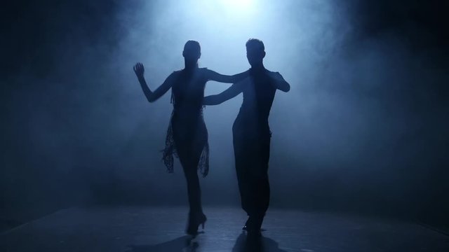 Dance element from the salsa, silhouette couple ballroom. Smoke background