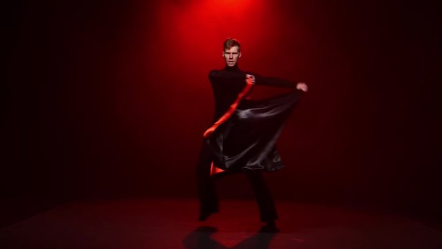 Red background. Man is dancing solo with red black cloth