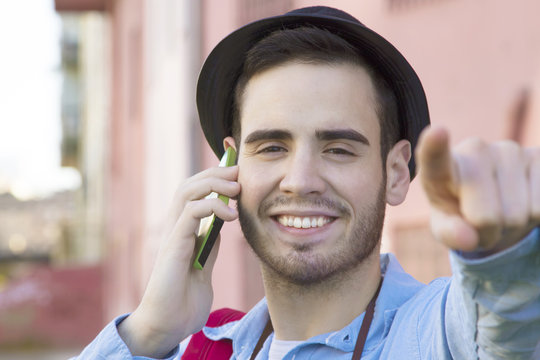 young man of style hipster talking on the phone on the street