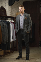 Elegant young handsome man with a beard in a white classic suit. The hotel's interior