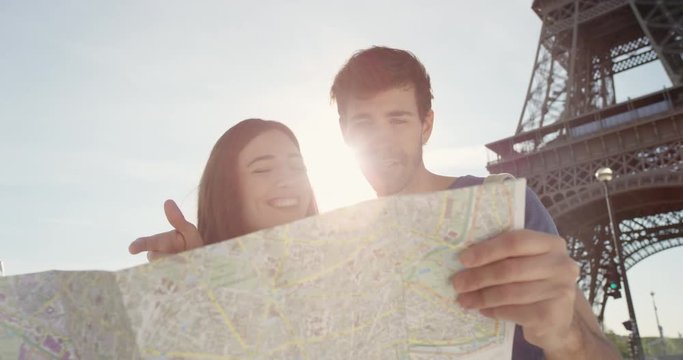 Tourist couple reading City Map under Eiffel Tower Paris planning European holiday Summer Vacation
