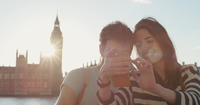 Tourist couple taking selfie photograph with smartphone in city at sunset sharing lifestyle photo enjoying  holiday European vacation travel adventure London