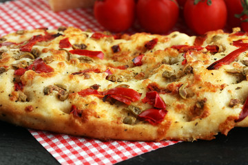 Hot pizza slice with melting cheese on a rustic wooden table.