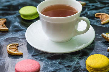 Still life with gingerbread nad macarons and tea on the black marble background