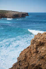 view on stunning surf spot from cliff ledge of bordeira beach by atlantic ocean with waves in blue sky, algarve, portugal