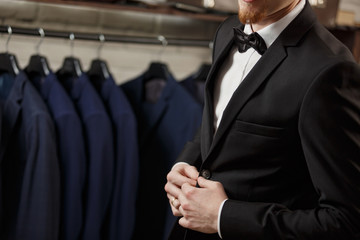 Fototapeta na wymiar Businessman in classic vest against row of suits in shop
