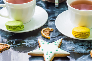 Still life with gingerbread nad macarons and tea on the black marble background