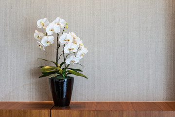 White flower vase placed on a wooden desk.