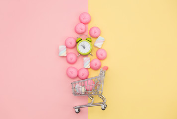 photo of marshmallows and alarm clock near shopping cart on the wonderful background in pop art style