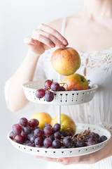photo of young woman holding stand with fruits on the wonderful white background