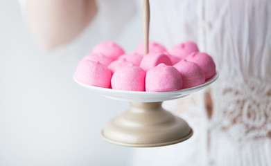 photo of young woman holding stand with pink marshmallows on the wonderful white background