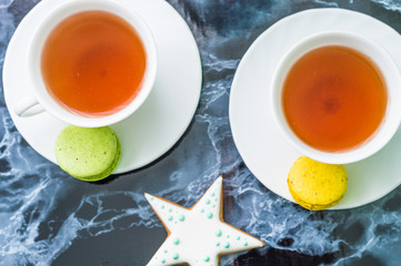 Still life with gingerbread nad macarons and tea on the black marble background