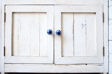 White vintage wooden cupboard with blue knobs