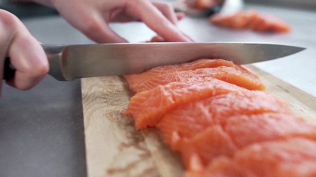 The cook cuts salmon fillet, chef prepares fish for cooking, dishes with fish, diet and healthy food