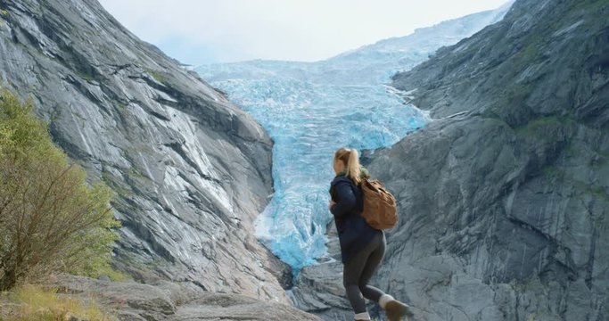 Woman with arms raised looking melting glacier view Hiking Girl lifting arm up celebrating scenic landscape enjoying vacation travel adventure nature Norway