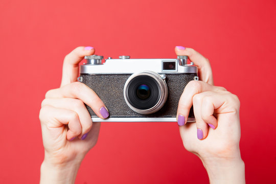 photo of female hand holding retro camera on the wonderful red background