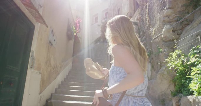 Happy Young Tourist Woman running up through street  in Italian town smiling and laughing POV travel concept Amalfi Coast Positano Italy Rear view