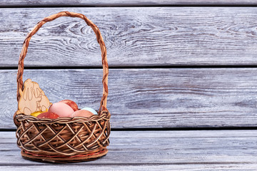 Fototapeta na wymiar Basket of eggs, wooden background. Plywood rabbits cutout.