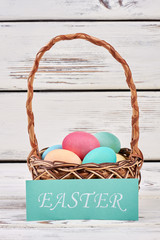 Easter card and egg basket. Basket on white wood surface.
