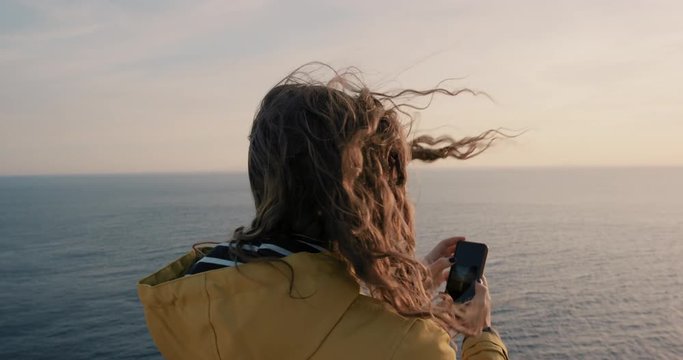 Woman taking photo of sunset with smartphone Girl photographing sunrise picture of ocean view with soft light landscape nature background enjoying vacation travel adventure 