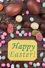 Happy Easter card with candies. Sweets on wood, top view.