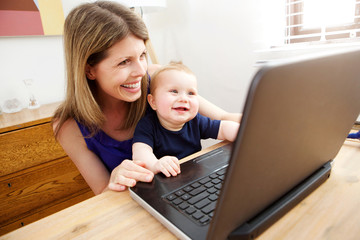 Fototapeta na wymiar mother and baby son enjoying using laptop together at home