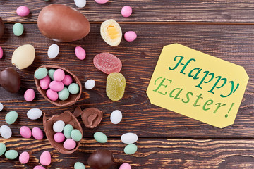 Scattered candies and Easter card. Sweets on dark wood.