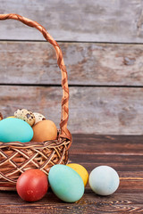 Easter wicker basket. Eggs on brown wooden background.