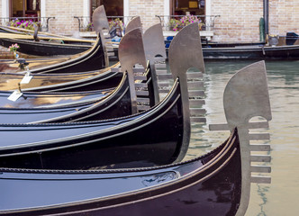 Beautiful row of metal bows of traditional Venetian gondolas anchored in a canal in the San Marco district, Venice, Italy © Marco Taliani
