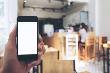 Mockup image of hand holding black mobile phone with blank white screen in wooden cafe